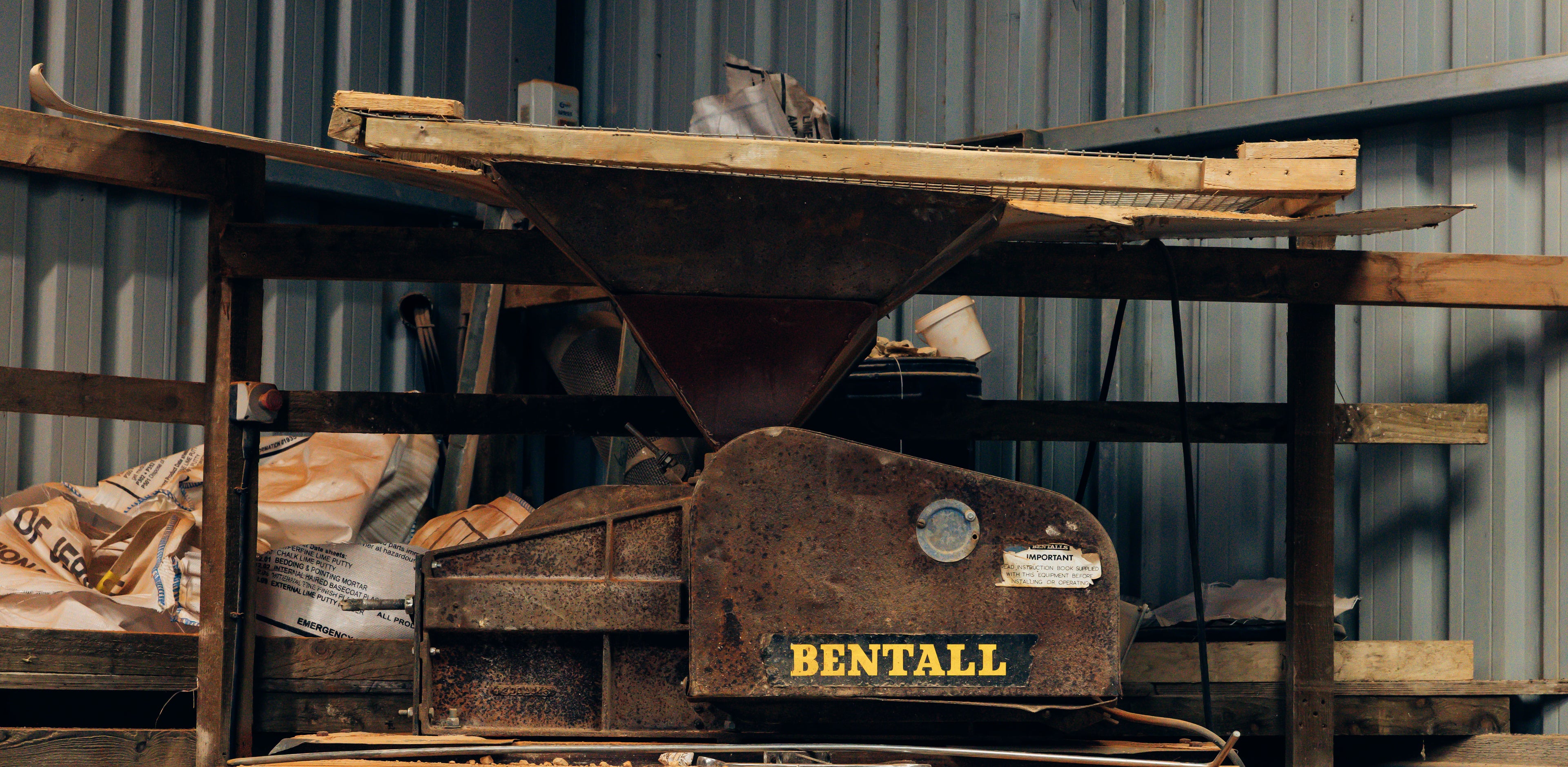 Rustic wooden table with a metal bin labeled 'Bentall' against a corrugated metal wall.